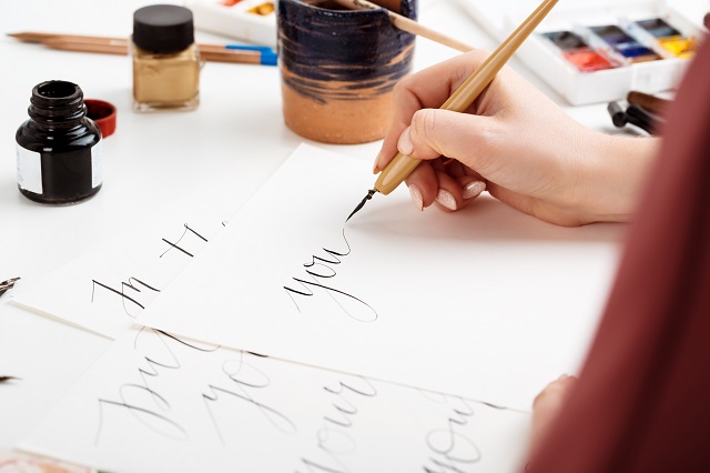 woman writing calligraphy on postcards