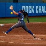 a softball player lunging forward to catch the ball