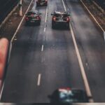 person holding a phone and the phone transitioning in to a road with cars